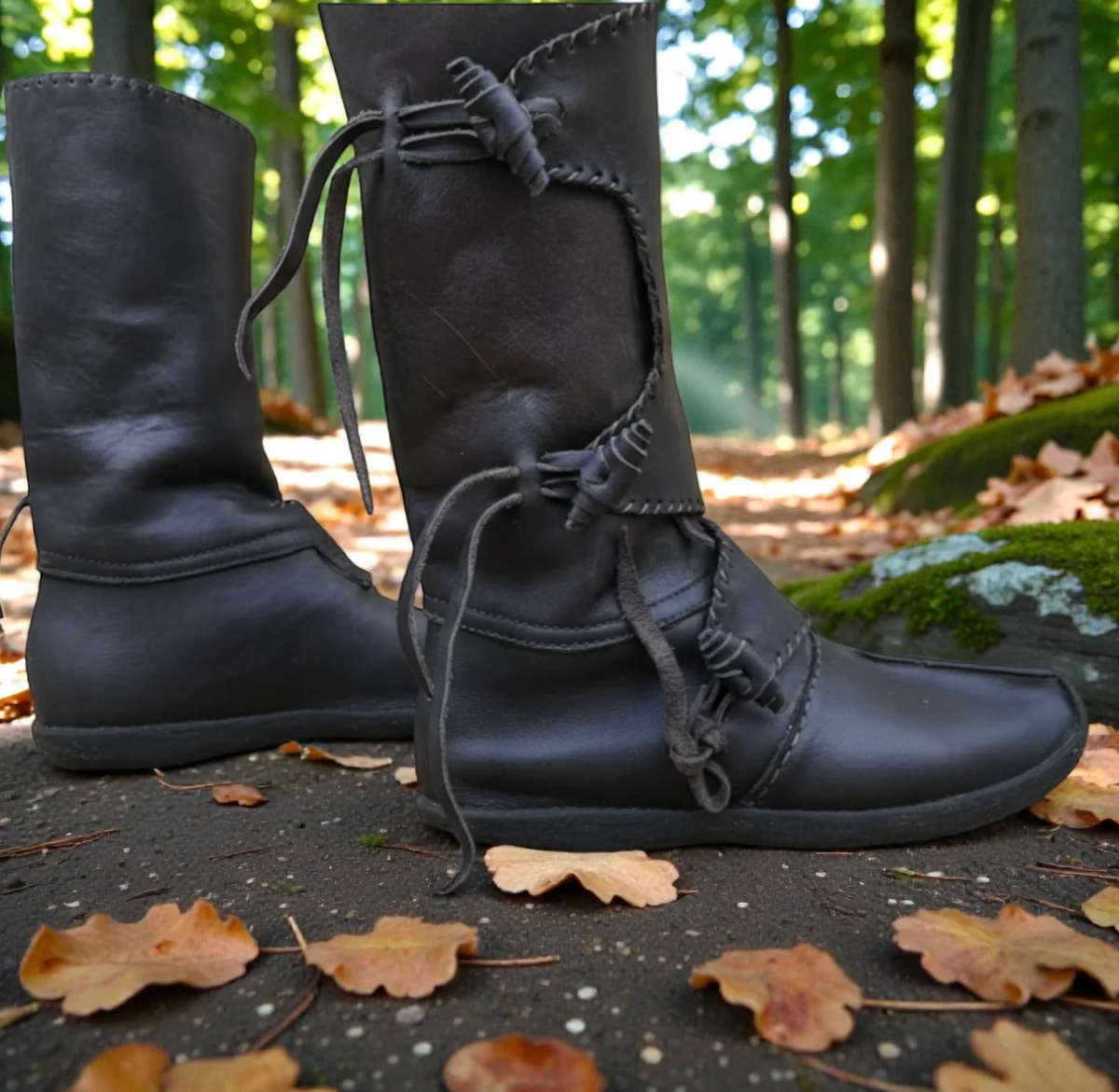 Black handmade medieval leather boots with wrap laces, set in a forest for LARP or SCA reenactment.